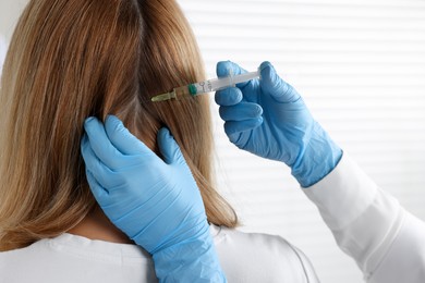 Trichologist giving injection to patient in clinic, closeup