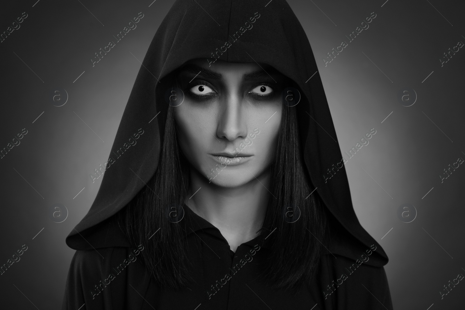 Photo of Mysterious witch with spooky eyes on dark background. Black and white effect