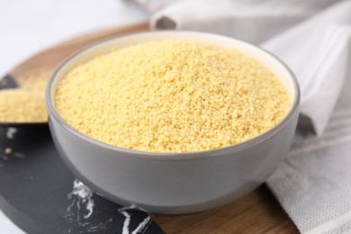 Photo of Raw couscous in bowl on table, closeup