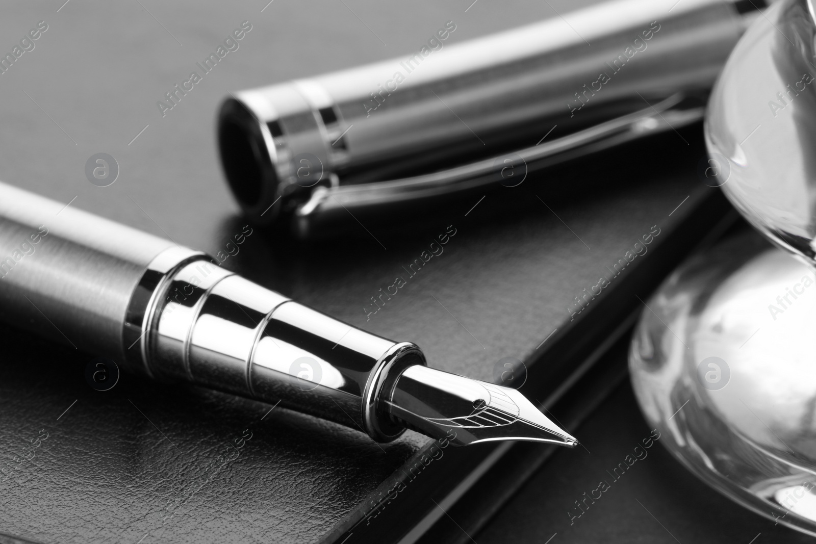 Photo of Stylish fountain pen, cap and leather notebook on table, closeup