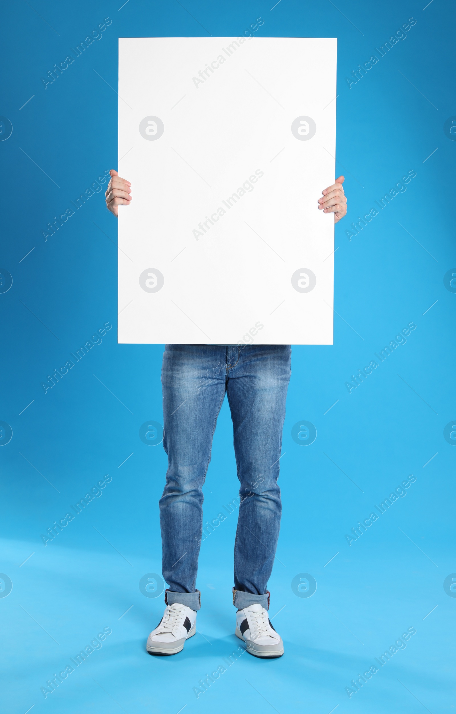 Photo of Man holding blank poster on blue background