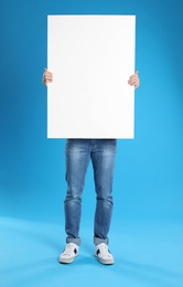 Man holding blank poster on blue background