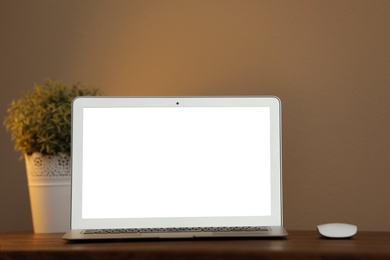 Photo of Laptop with blank screen on table indoors. Space for text