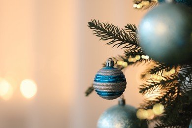 Photo of Christmas tree decorated with light blue festive balls on blurred background, closeup. Space for text