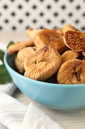 Photo of Bowl with tasty dried figs on white wooden table, closeup