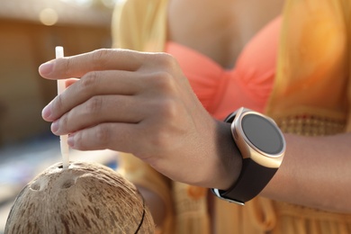 Photo of Woman wearing modern smart watch outdoors, closeup