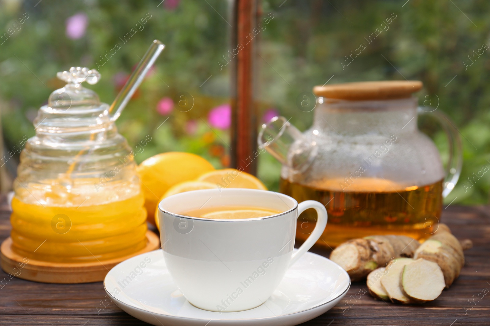 Photo of Cup of delicious tea with lemon and honey on wooden table