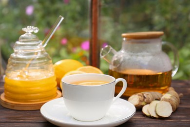 Cup of delicious tea with lemon and honey on wooden table