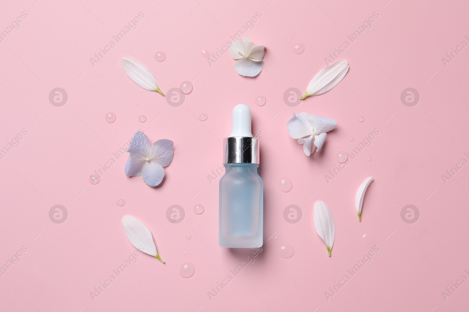 Photo of Bottle of cosmetic serum and beautiful flowers on pink background, flat lay