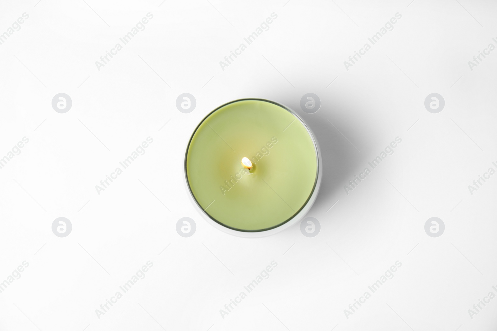 Photo of Green wax candle in glass holder isolated on white, top view