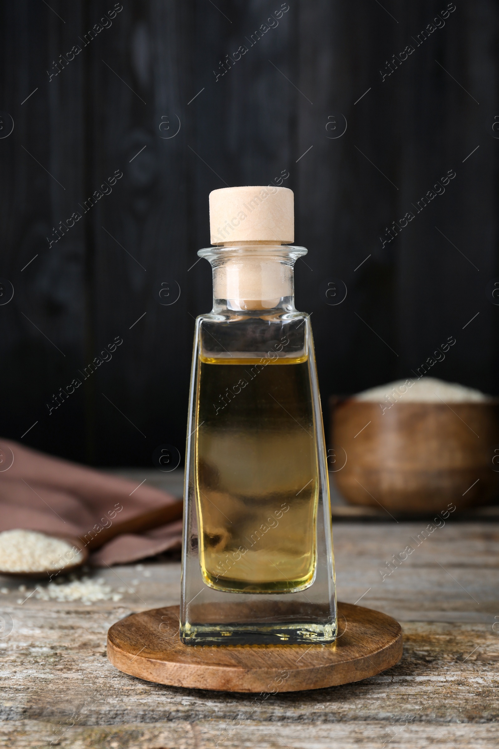 Photo of Bottle of organic sesame oil on wooden table, closeup