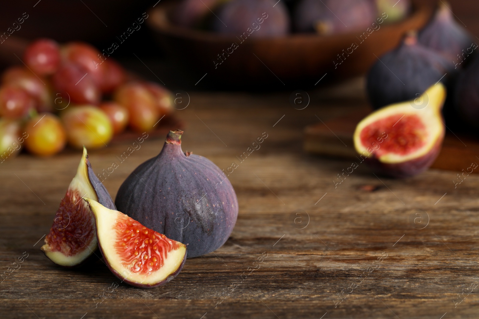 Photo of Whole and cut tasty fresh figs on wooden table. Space for text