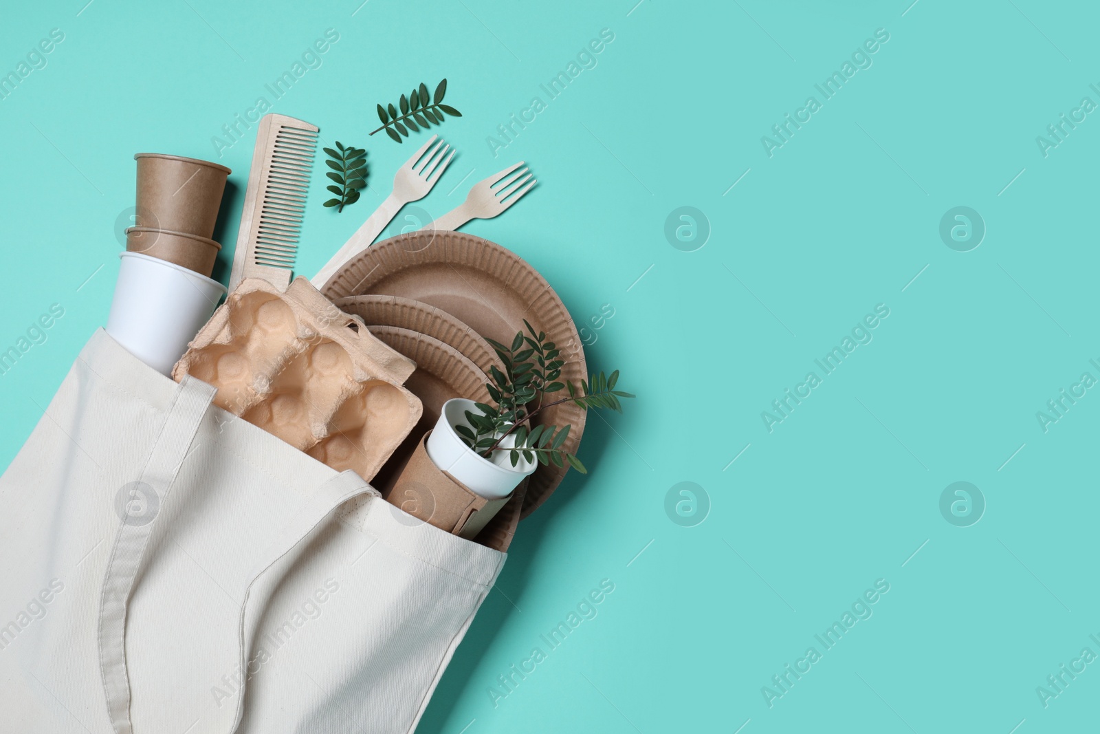 Photo of Eco bag with different disposable items on turquoise background, flat lay and space for text. Recycling concept