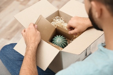 Young man opening parcel at home, closeup