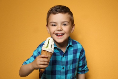 Photo of Adorable little boy with delicious ice cream against color background