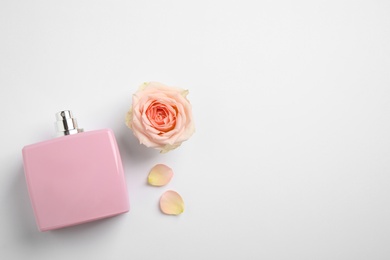 Photo of Bottle of perfume, beautiful rose and petals on white background, flat lay