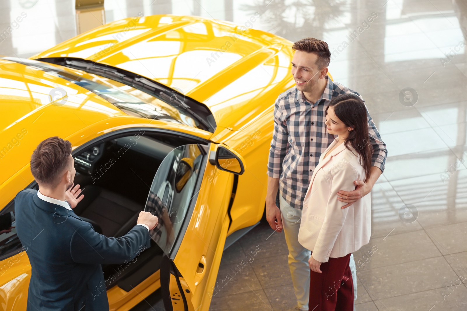 Photo of Young couple buying new car in salon