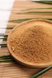 Photo of Coconut sugar, palm leaves and bamboo mat on table, closeup