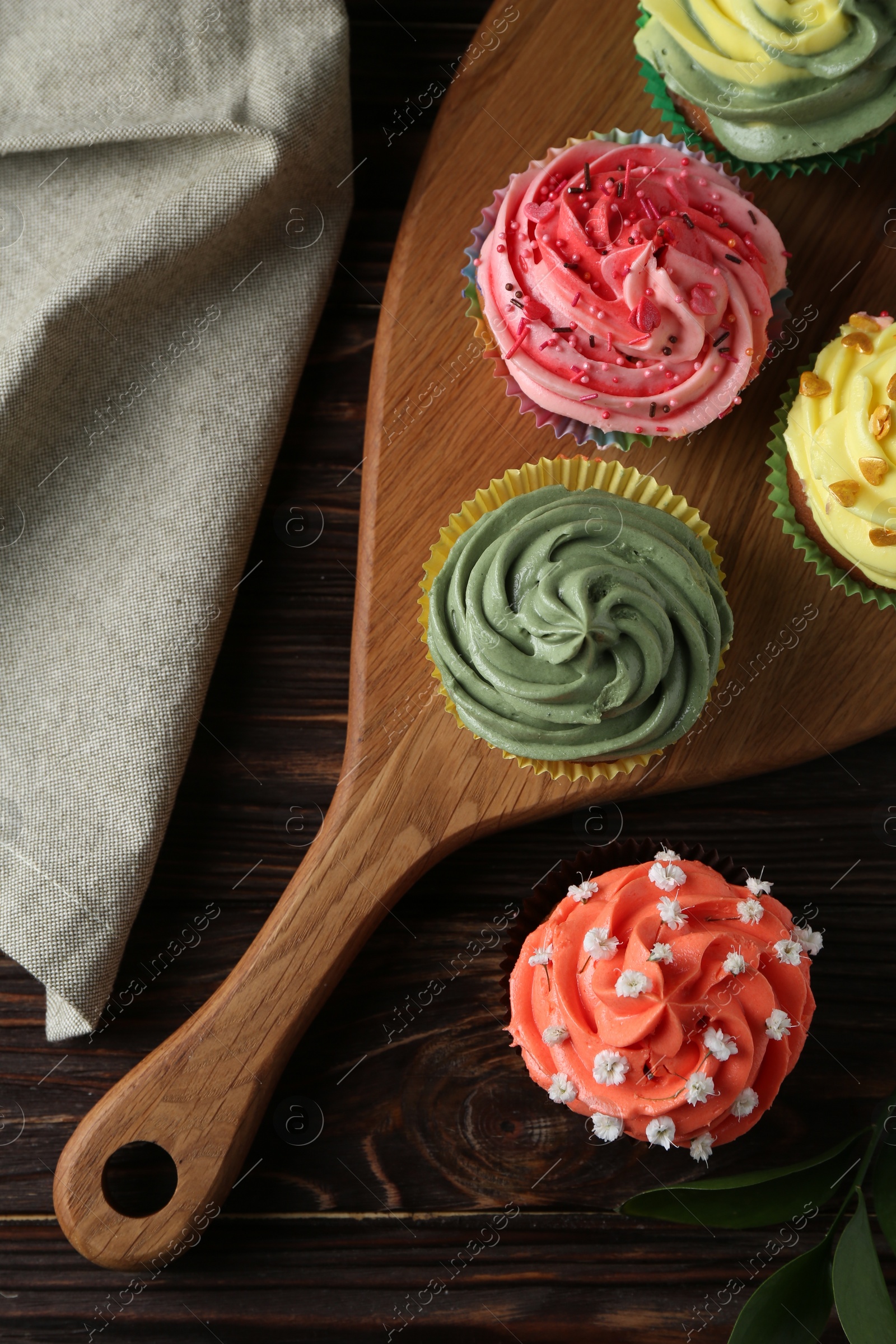 Photo of Delicious cupcake with bright cream on wooden table, flat lay