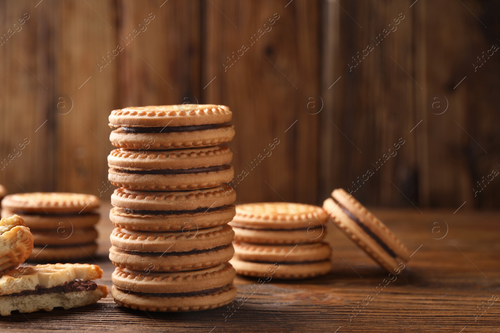 Photo of Tasty sandwich cookies with cream on wooden table, closeup. Space for text