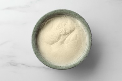 Photo of Bowl of agar-agar powder on white marble table, top view