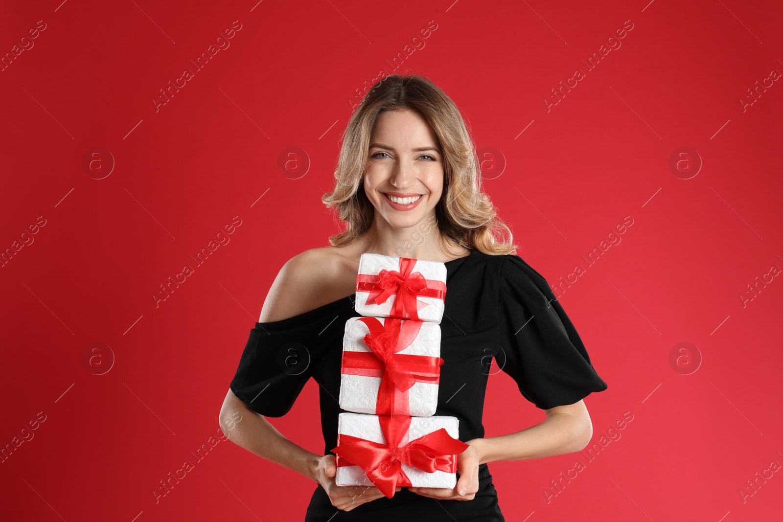 Photo of Beautiful young woman with Christmas presents on red background