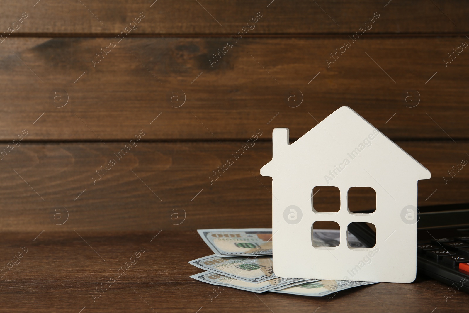 Photo of Mortgage concept. House model, calculator and money on wooden table, space for text