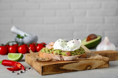 Photo of Delicious sandwich with guacamole, shrimps and fried egg on light grey table. Space for text