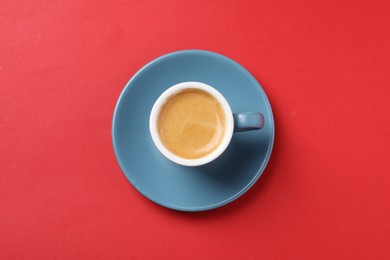 Aromatic coffee in cup on red background, top view