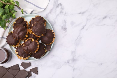 Delicious profiteroles with chocolate and mint on white marble table, flat lay. Space for text