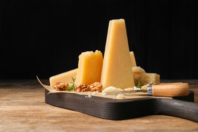 Photo of Delicious parmesan cheese with walnuts and rosemary on wooden table