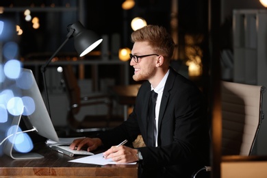 Concentrated young businessman working in office alone at night