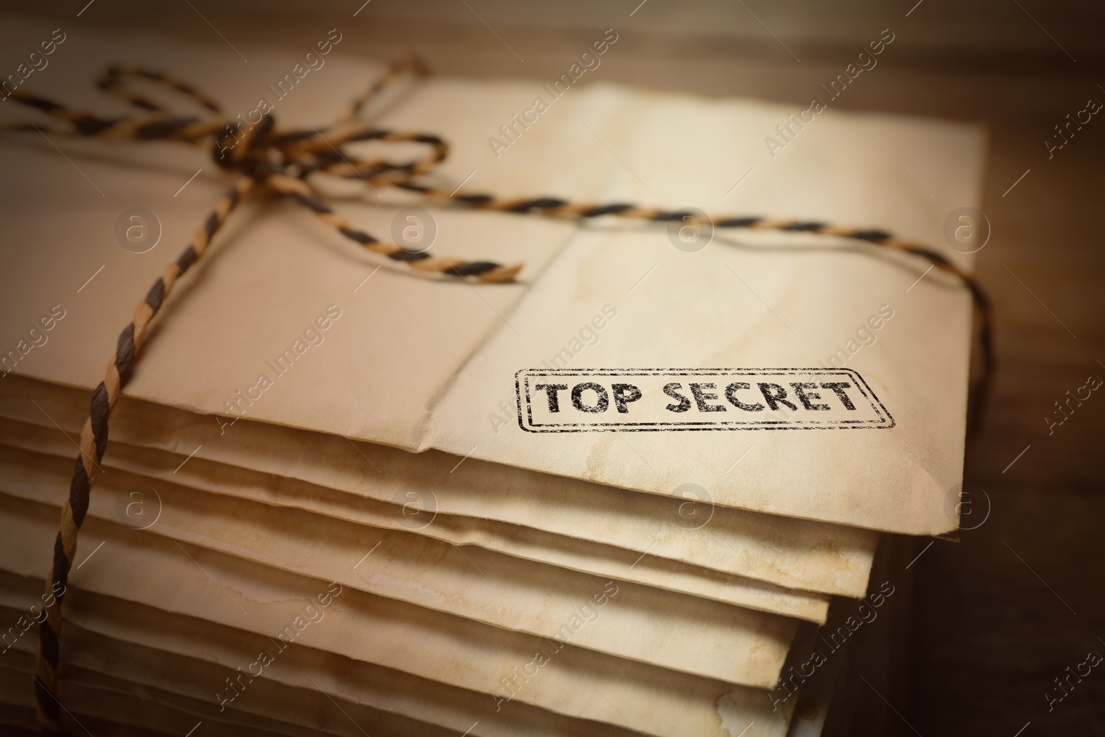 Image of Top Secret stamp. Stacked old letters tied with string on table, closeup