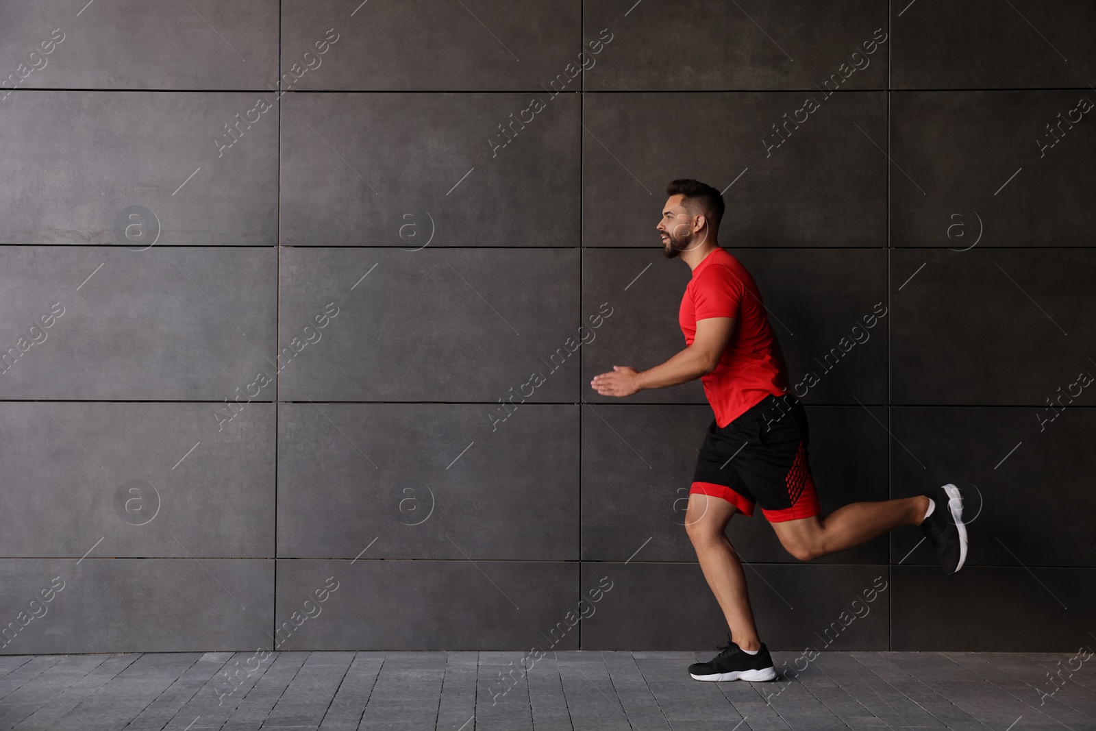 Photo of Young man running near building outdoors. Space for text