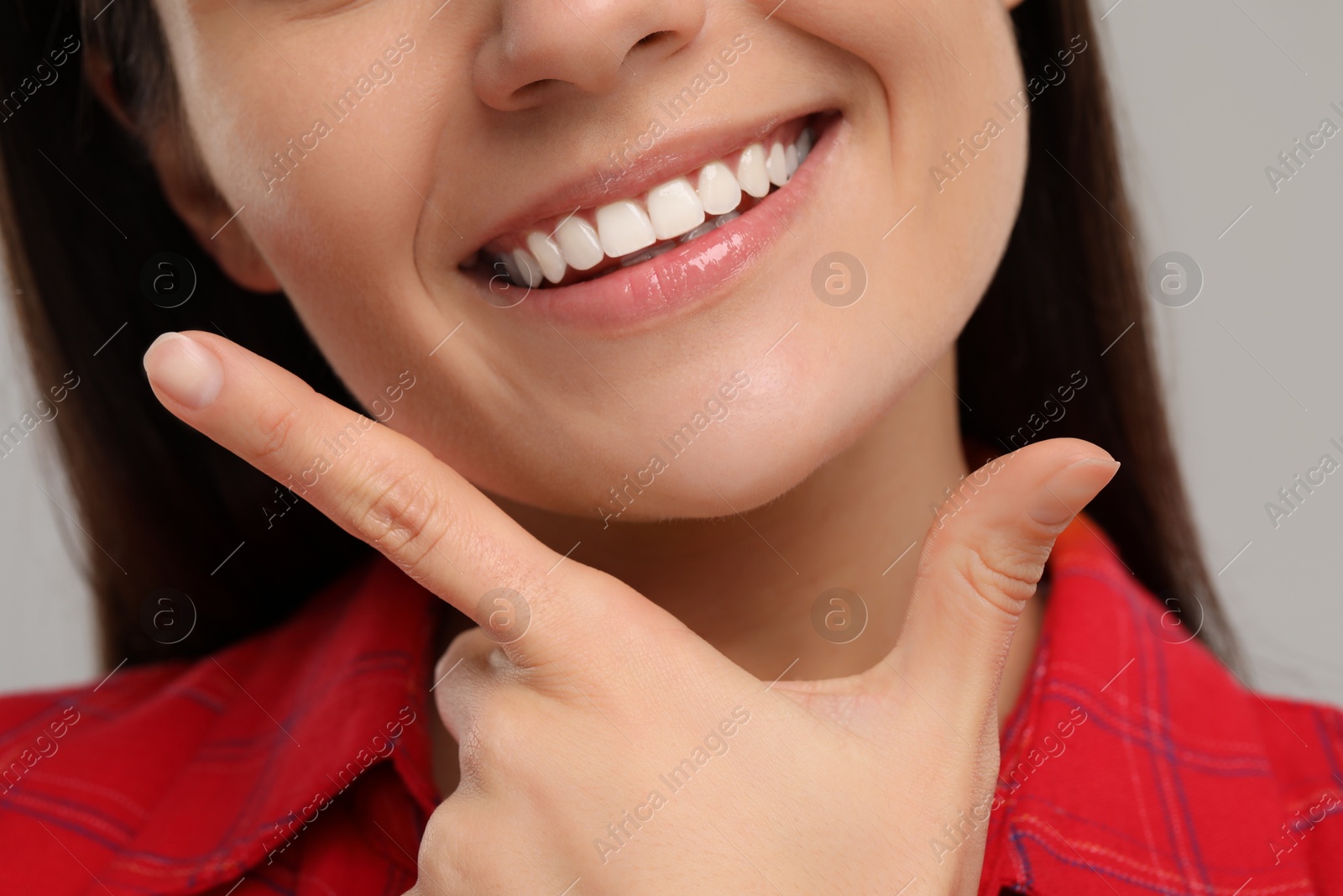 Photo of Young woman with clean teeth smiling on light grey background, closeup