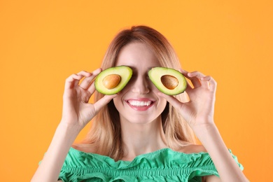 Portrait of young beautiful woman with ripe delicious avocado on color background