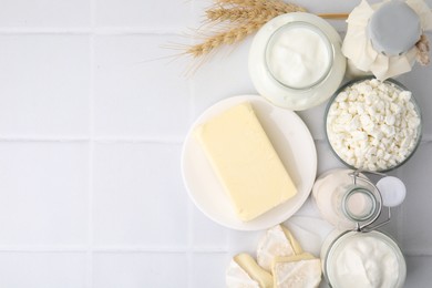 Photo of Different dairy products and spikes on white tiled table, flat lay. Space for text