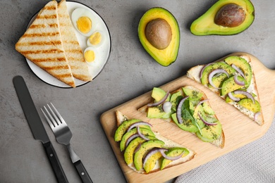 Photo of Flat lay composition with avocado toasts on grey table