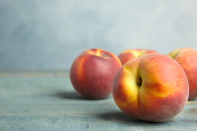 Photo of Fresh juicy peaches on wooden table against blue background, space for text