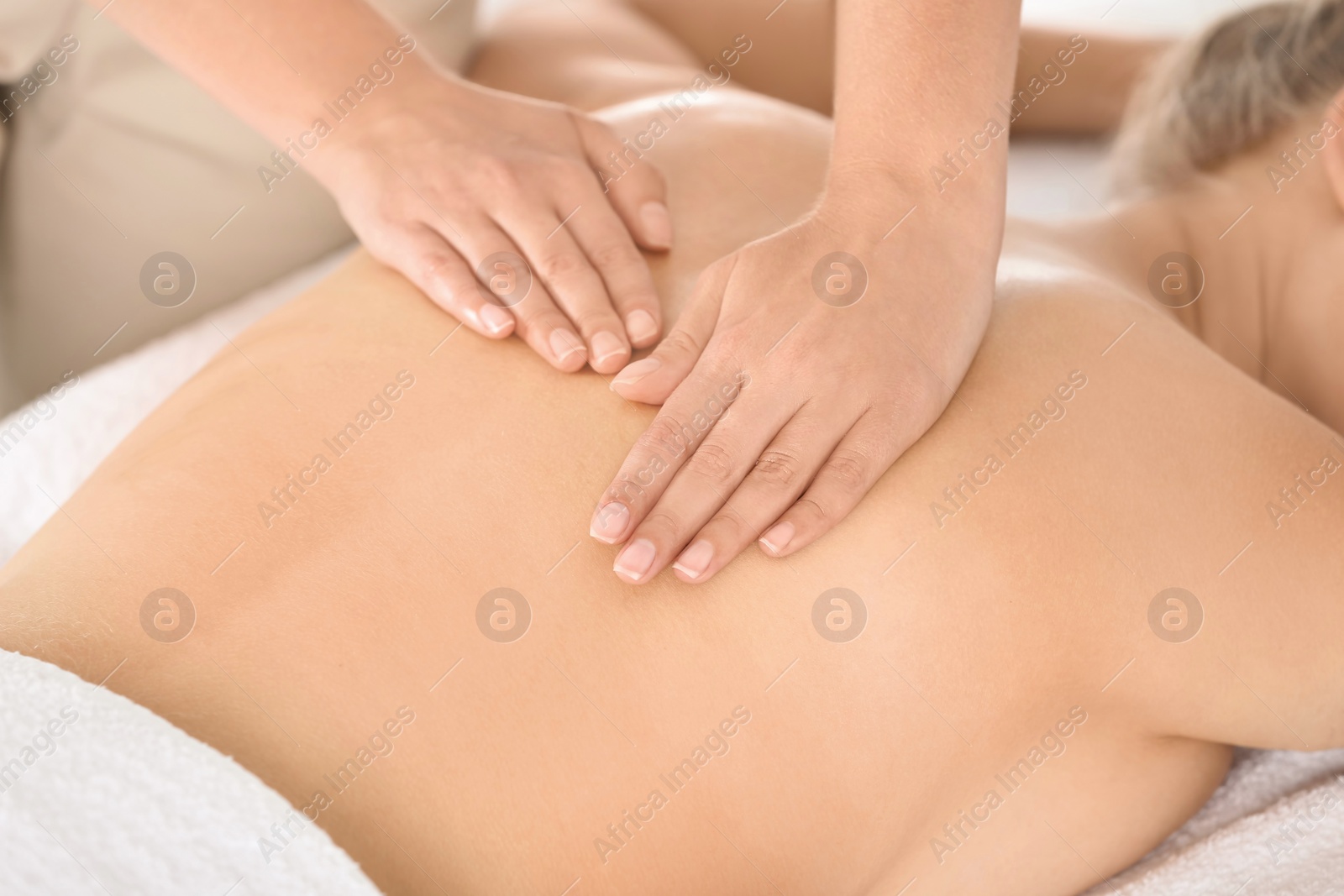 Photo of Relaxed woman receiving back massage in wellness center