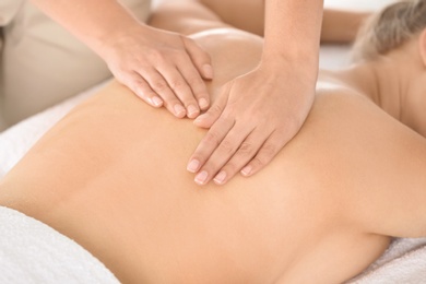 Photo of Relaxed woman receiving back massage in wellness center