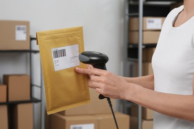 Photo of Seller with scanner reading parcel barcode in office, closeup. Online store