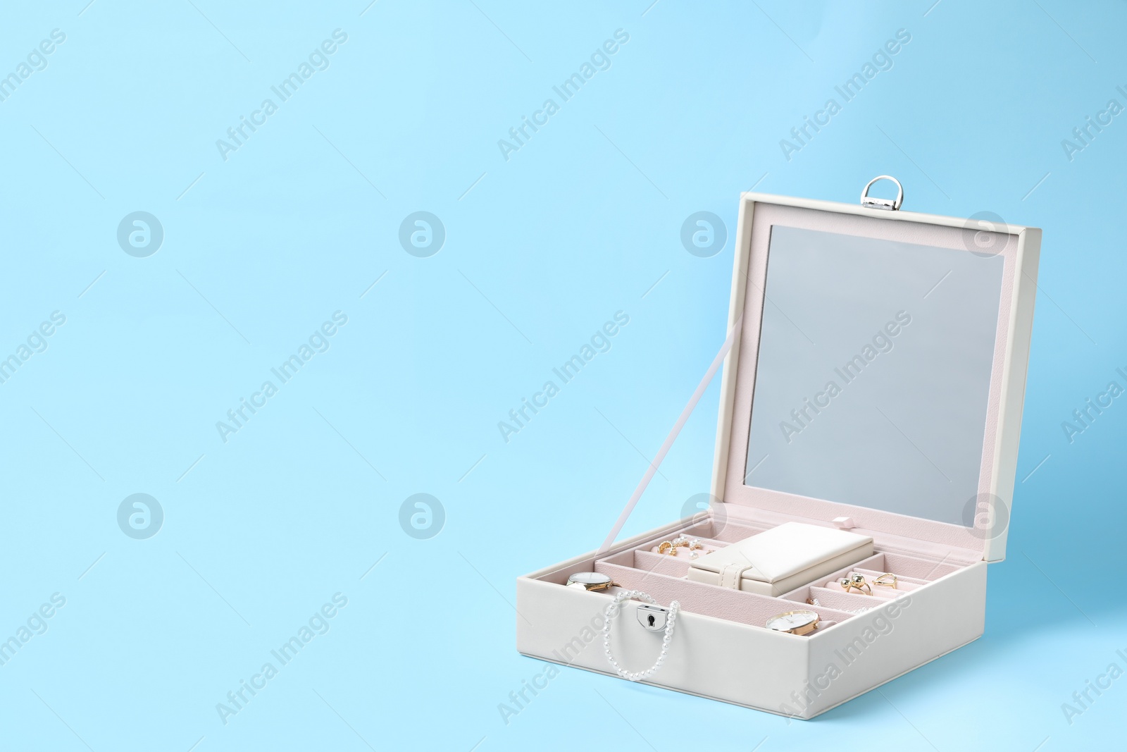 Photo of Jewelry box with many different accessories on light blue background, space for text