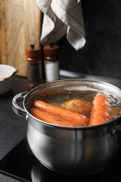 Photo of Boiling carrot and potatoes in pot on electric stove. Cooking vinaigrette salad