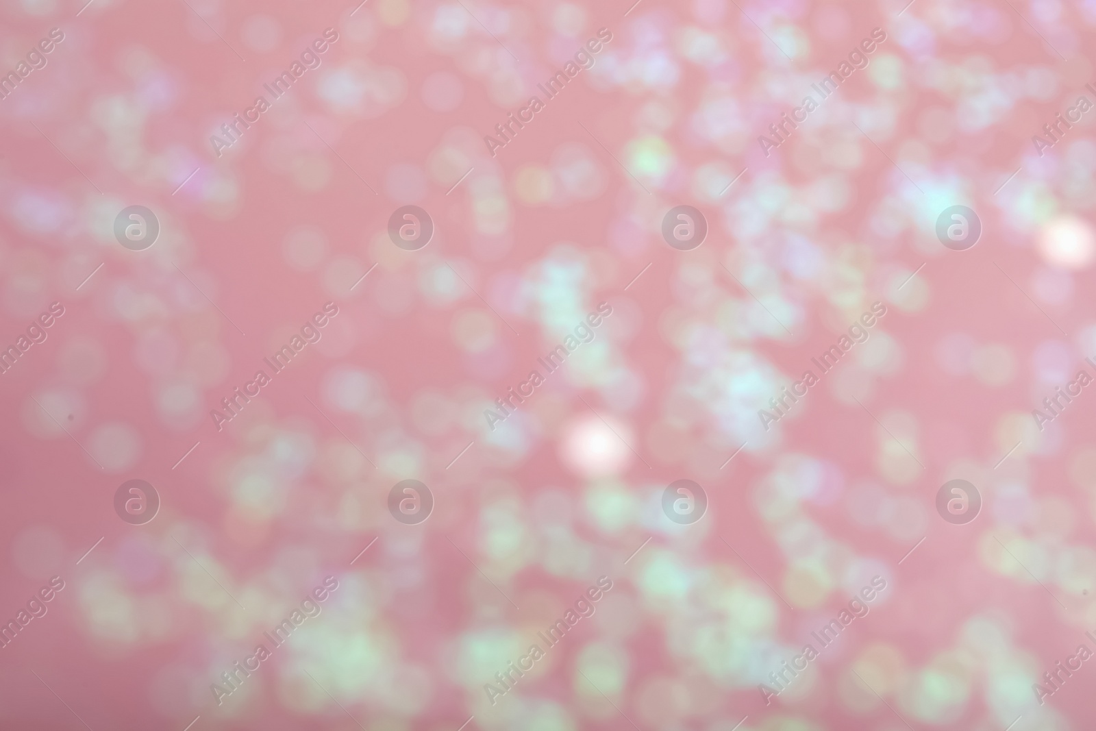 Photo of Blurred view of white glitter on pink background. Bokeh effect