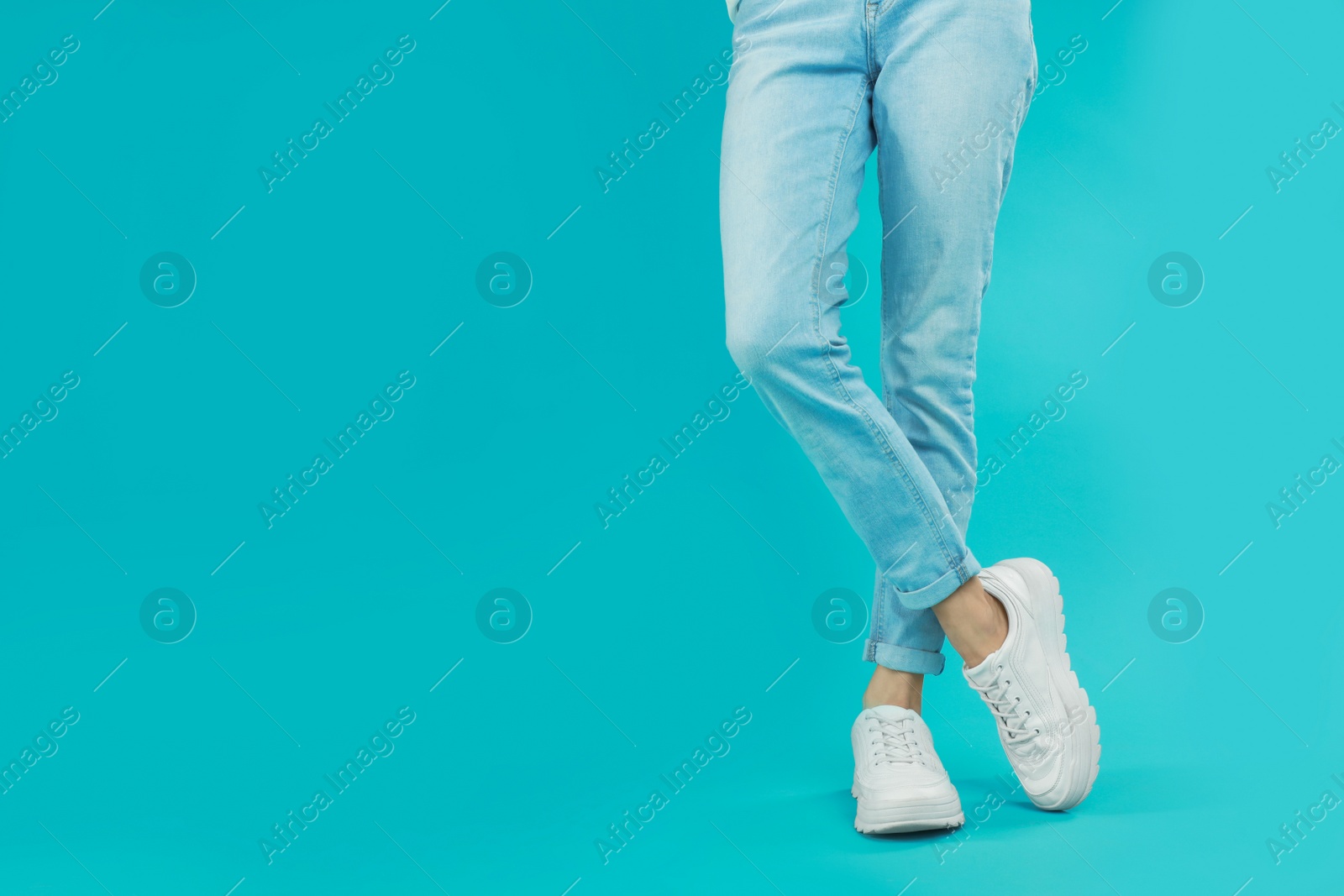 Photo of Woman in stylish sport shoes on light blue background. Space for text