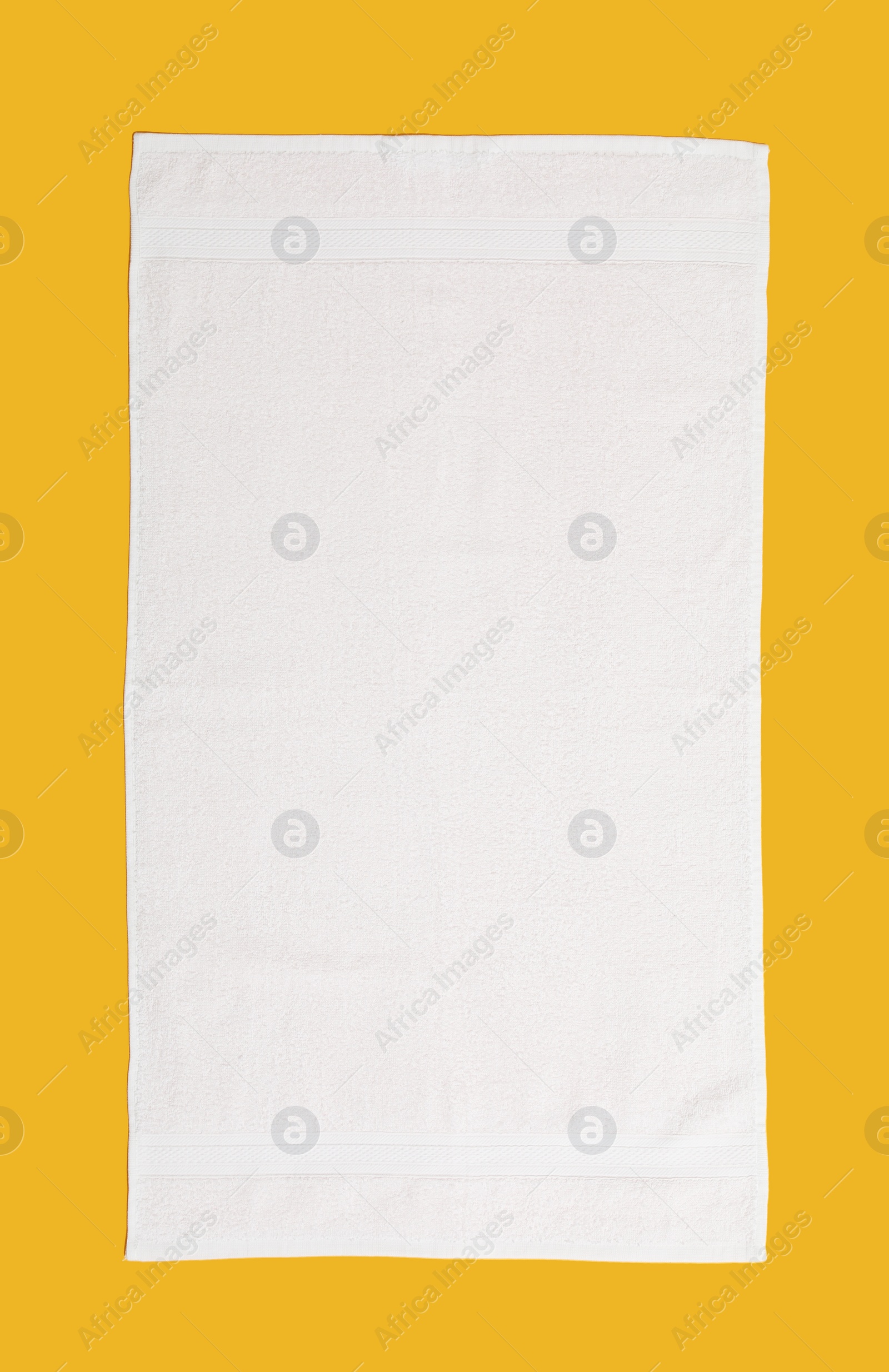 Photo of White beach towel on yellow background, top view