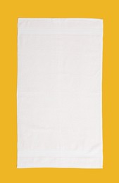 Photo of White beach towel on yellow background, top view