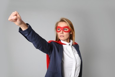 Photo of Confident businesswoman wearing superhero cape and mask on light grey background