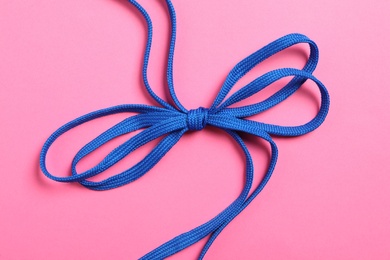 Photo of Blue shoelaces on pink background, top view